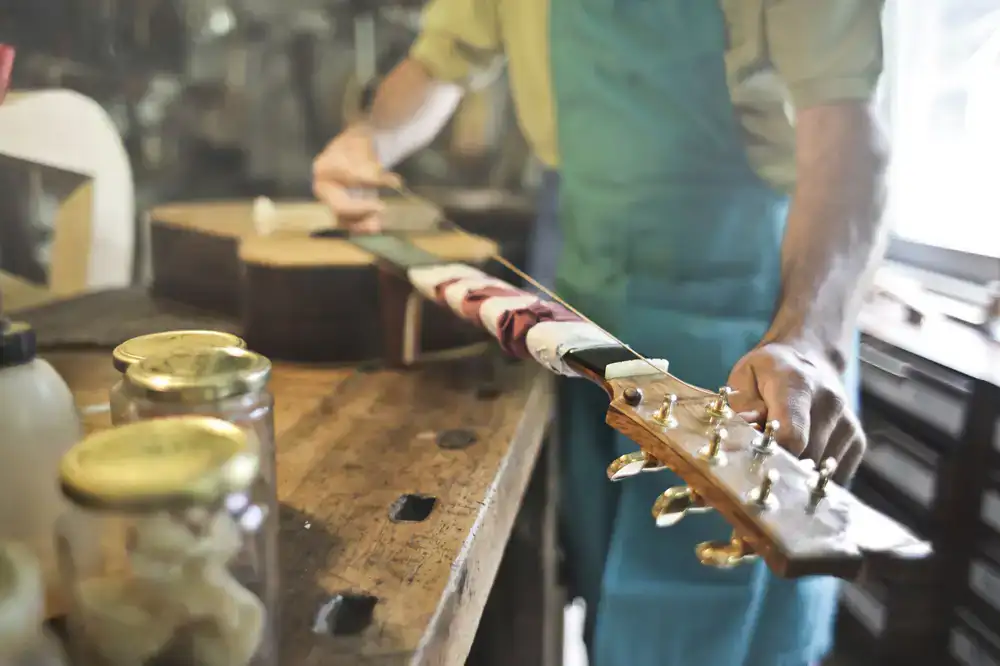Luthier carefully adjusting a vintage acoustic guitar at the workbench