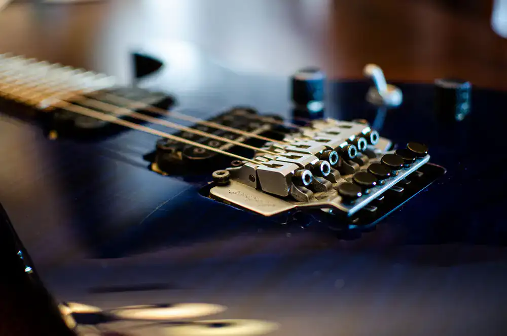 Close up view of a guitar bridge being adjusted with specialized tools